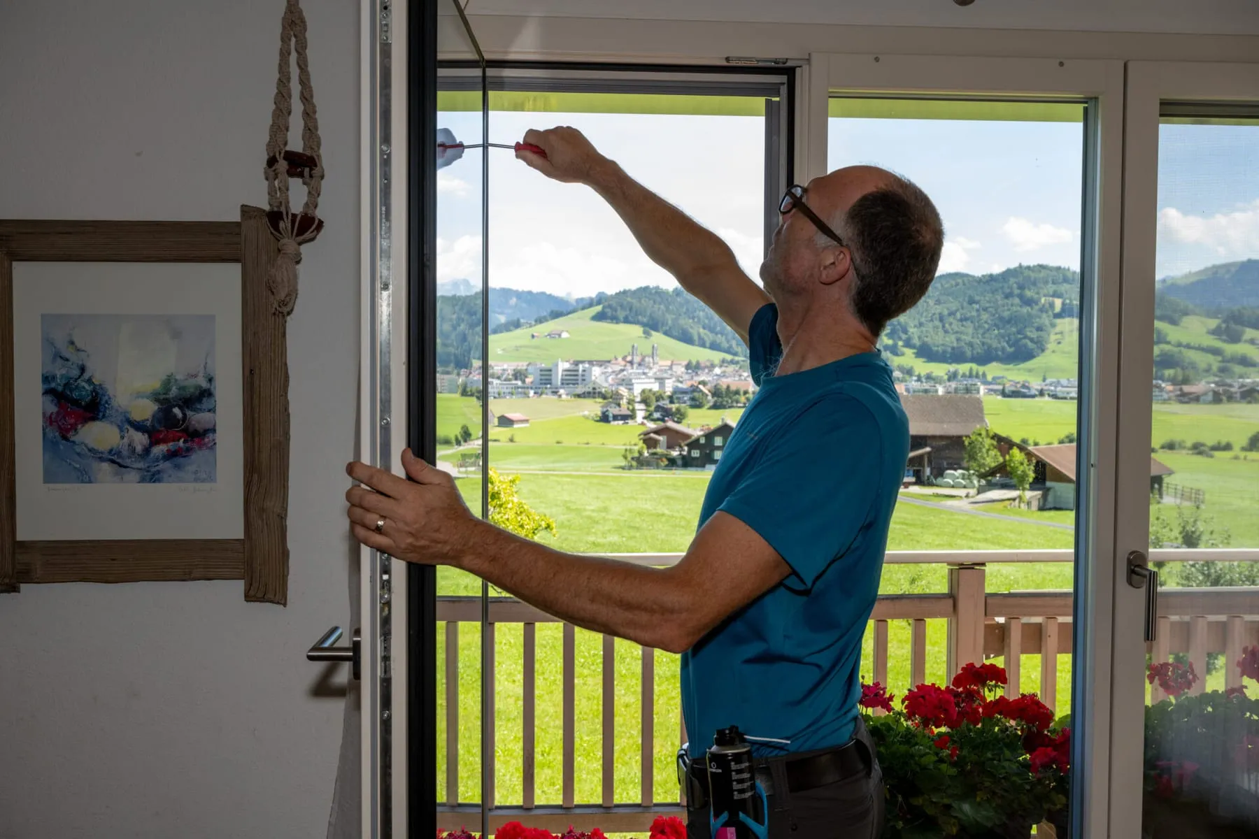 Martin Röllin stellt den oberen Beschlag einer Balkontüre nach, Blick über Einsiedeln