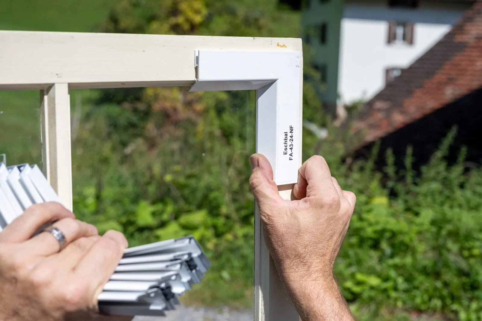 Metallschale wird auf den Aussenrahmen eines Holzfensters gesetzt, im Hintergrund ein Bauernhaus